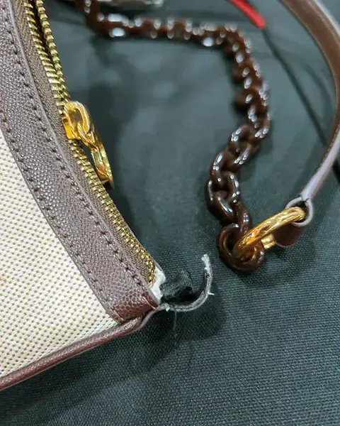 Handbag with a broken chain strap fitting, before repair