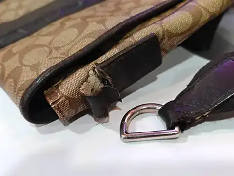 Bag with a split leather tab and a loose D-ring, before repair