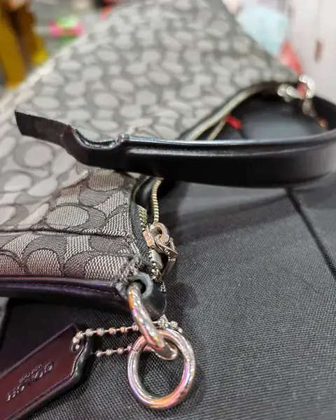 Shoulder bag with the strap tab torn from the ring, before repair