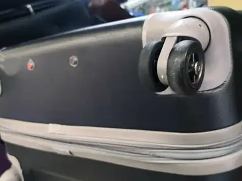 A hard-shell suitcase with a new spinner wheel fitted at KL Cobbler & Locksmith