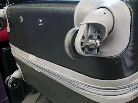Hard-shell suitcase with a broken wheel, before repair