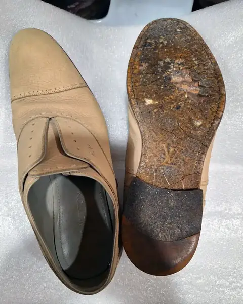 Leather shoe with a worn-through sole and heel, before repair
