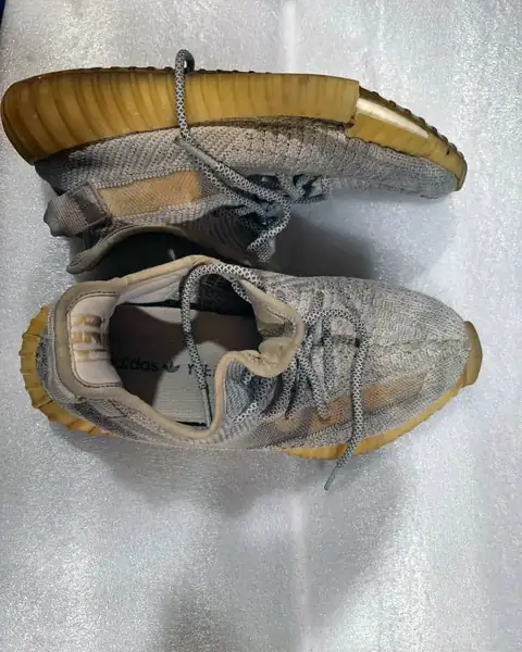 Knit sports shoes with worn, discoloured soles, before repair